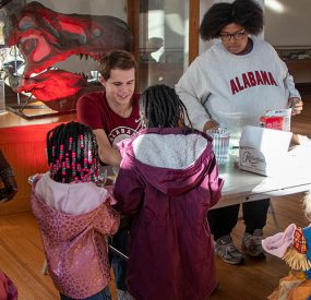 UA students help young children with science experiment